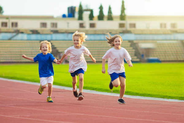 Child running in stadium. Kids run. Healthy sport.